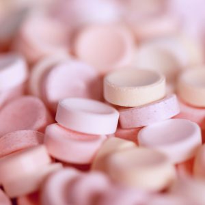 Developmental Editing. Small, round, pastel pink and orange candy, some in focus and some out of focus.